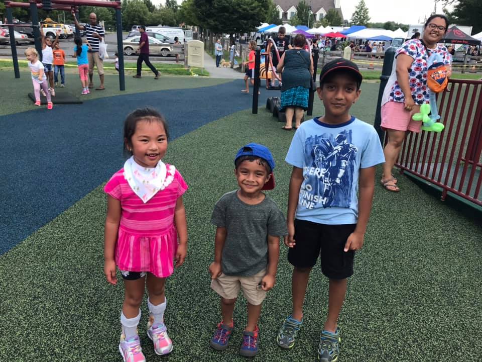 Two boys and a girl posing for the picture on the playground.