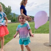 Image of a girl smiling and holding the pink balloon.
