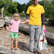 Image of a man holding the girl standing on a log.