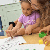 Woman helping girl coloring.